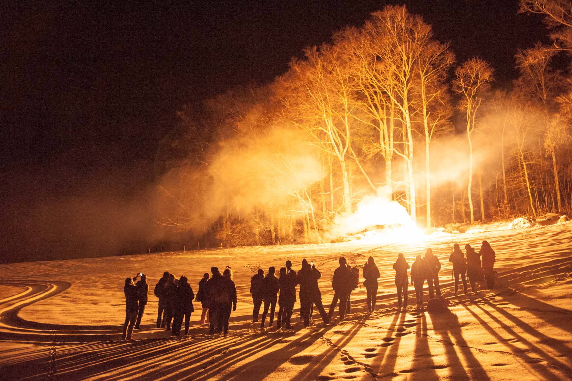 Menschen bestaunen ein Pyro-Feuerwerk im Schnee.