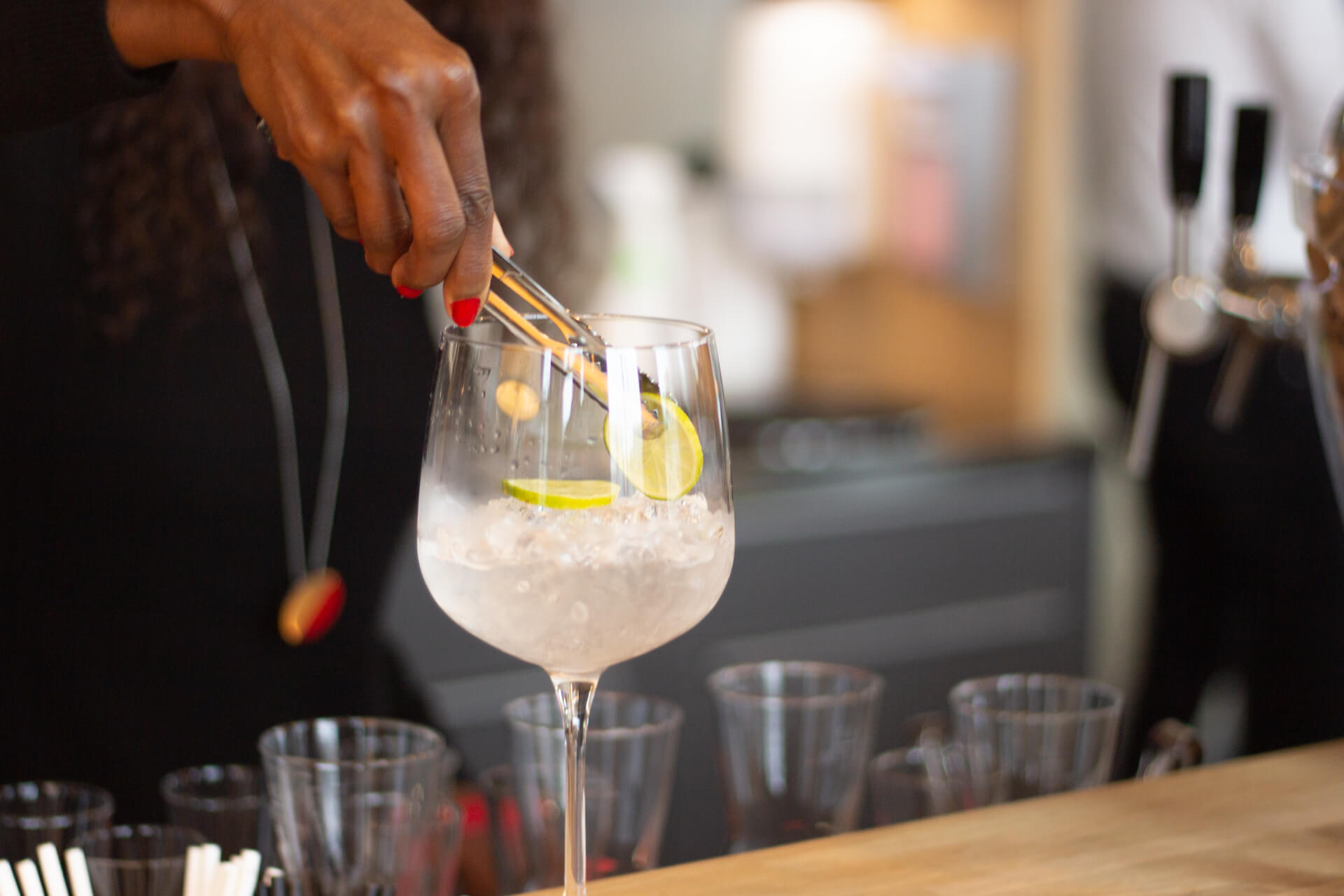Drink mixen: Der Limetten-Schnitz wird mit einer Pinzette vorsichtig in das Glas gelegt.
