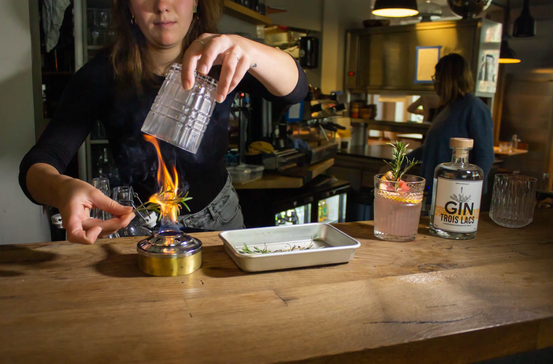 Rosmarin wird über einer Flame geröstet und der Rauch wird im Glas darüber eingefangen.